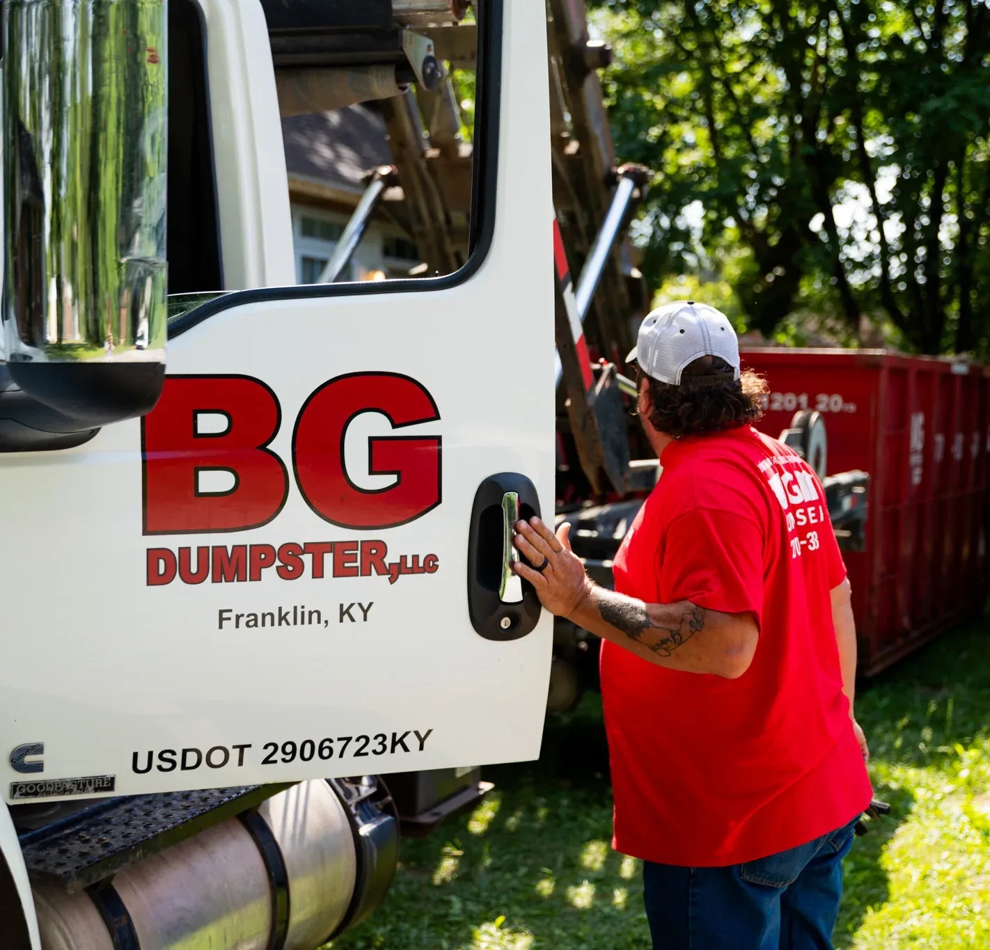 A BG Dumpster team member beside a branded delivery truck at a customer property