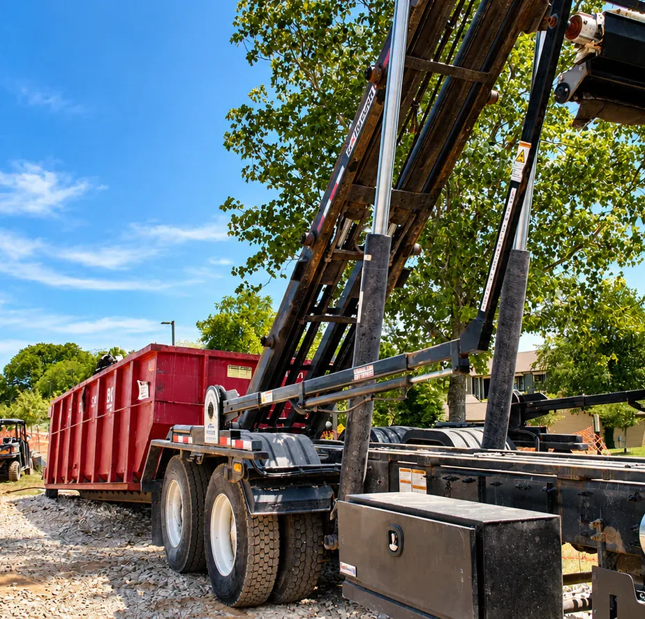 A BG Dumpster roll-off truck and red dumpster at a construction site