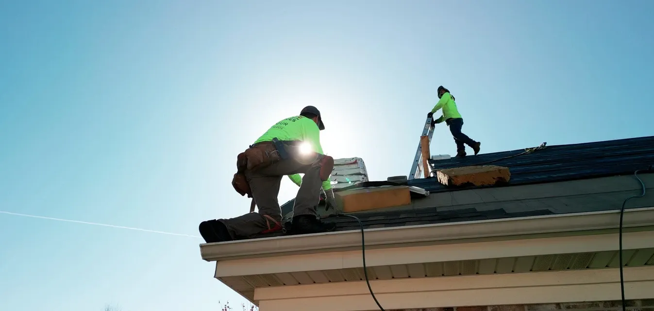 A roll-off dumpster positioned beside an active roofing and renovation project